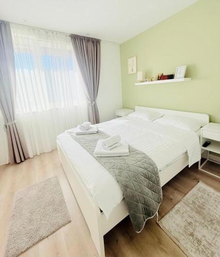 a white bedroom with two beds and a window at Modern Apartment in City Center in Iaşi