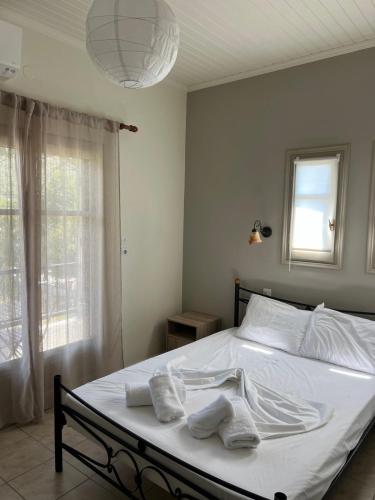 a bedroom with a bed with white sheets and a window at Kanarinia Guesthouse in Kala Nera