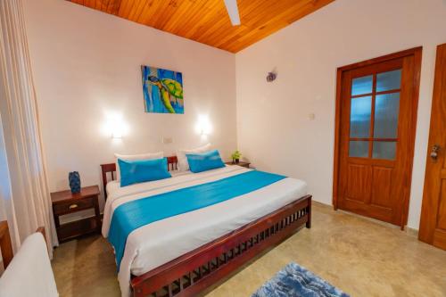 a bedroom with a large bed with blue pillows at Villa Comfort in Hikkaduwa