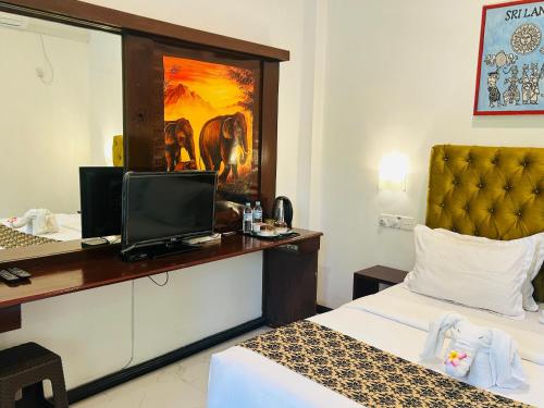a hotel room with a bed and a desk with a computer at Inn Sea Horizon Ahungalla in Ahungalla