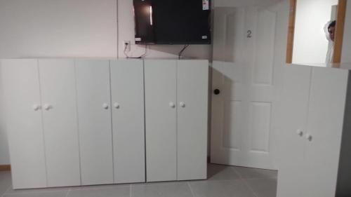 a kitchen with white cabinets and a flat screen tv at Hostal GYT in Caldera