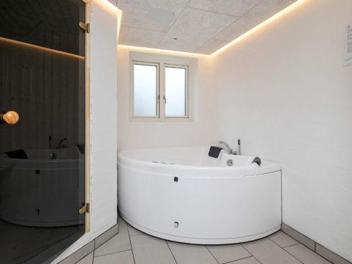 a white bathroom with a tub and a sink at 14 person holiday home in Løkken in Løkken