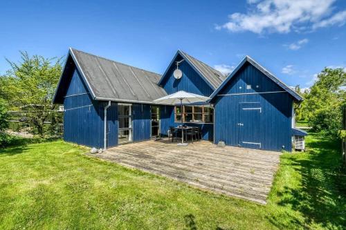 a blue barn with a wooden deck in the yard at C11693-Hemmet-Bork-Hytteby-144 in Falen
