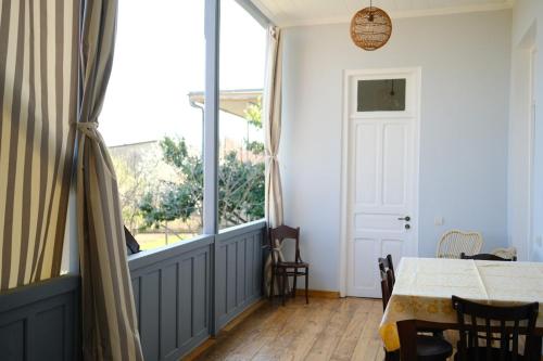 a dining room with a table and a large window at Entire House & Garden - Chokhelis' Telavi Retreat in Tʼelavi