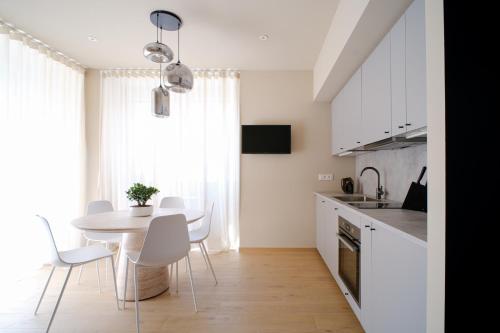 a kitchen with a table and white chairs in a room at Premier Stay The Garden - Bernina Experience in Tirano