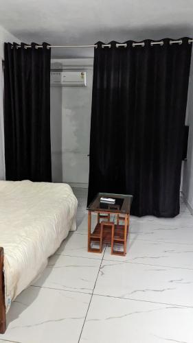 a bedroom with a bed and a table with a black curtain at Anam residence in Tāzhekkod