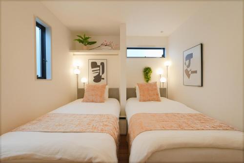 two beds in a small room with two windows at Tomo House 四谷三丁目 301 in Tokyo