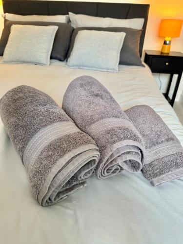 a pile of towels on top of a bed at Brand-new flat, King Bed, Sofa Bed with full kitchen, Wi-Fi, self check-in Central location near everything in Farnborough