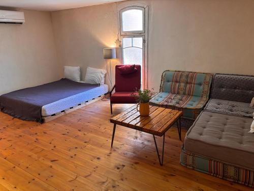a room with a bed and a couch and a table at בקתת הבוסתן in Bet HaShitta