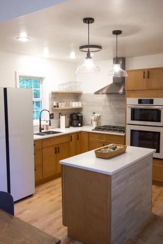 a kitchen with wooden cabinets and a white refrigerator at Lincolnville 2BR - Beach Vibes & Backyard BBQ in Lincolnville