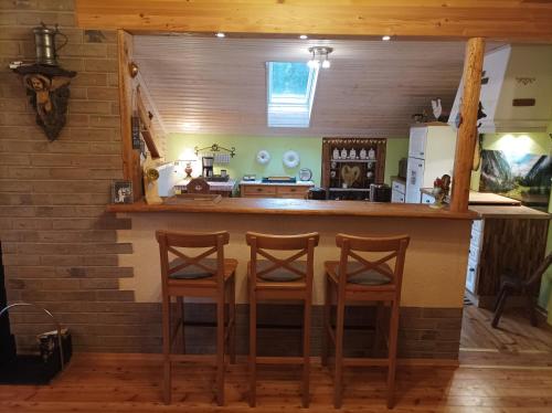 a kitchen with a bar with three stools at Ferienwohnungen Dopplerhof in Piding