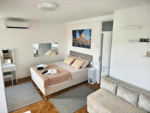 a bedroom with a king sized bed and a couch at Apartman Horizont in Arandjelovac