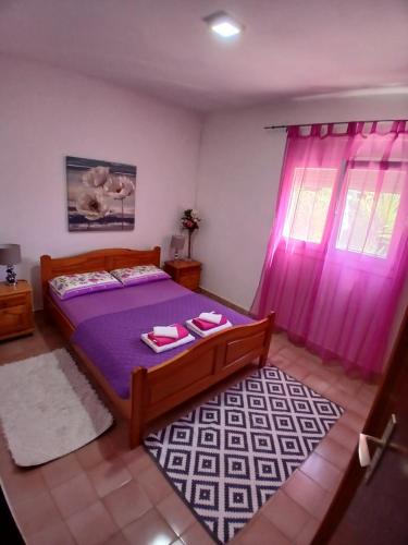 a bedroom with a bed with purple sheets and pink curtains at DosPalmeras in Vir
