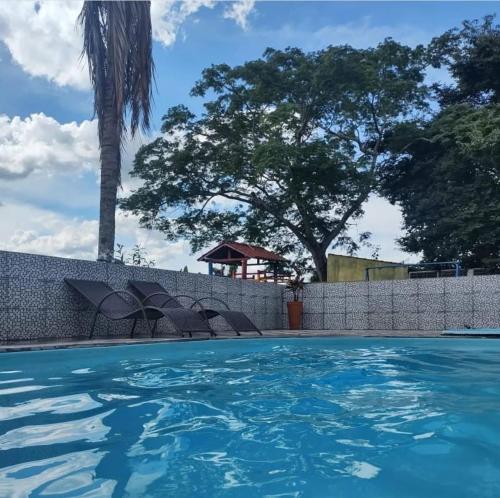 une piscine avec des chaises et des arbres en arrière-plan dans l'établissement Pousada Portal da Serra, à São João Batista do Glória