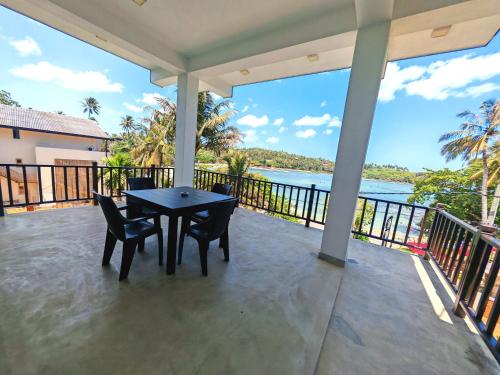 a porch with a table and chairs and a view of the water at Waves Hiri Sea View in Hiriketiya