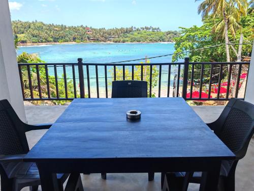 a blue table with chairs and a view of the ocean at Waves Hiri Sea View in Hiriketiya