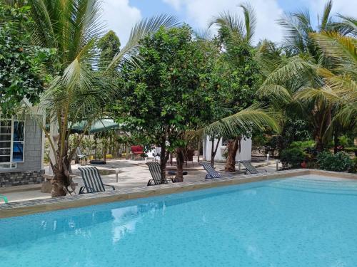 a swimming pool with chairs and palm trees at Escape Hole in Diani Beach