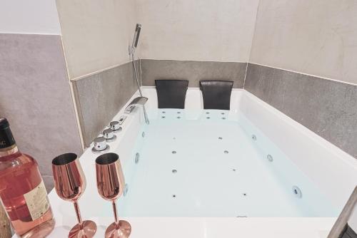 a white bath tub with wine glasses sitting next to it at LES BULLES DE MONA - Alcove - Spa - Clim in Lyon