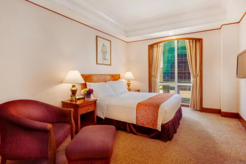 a hotel room with a bed and a chair and a window at Richmonde Hotel Ortigas, Manila in Manila