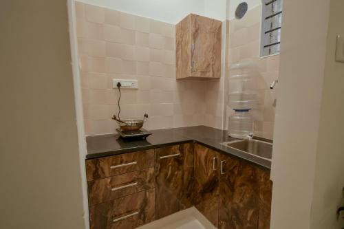 a small kitchen with wooden cabinets and a sink at HomeSlice Whitefield in Bengaluru