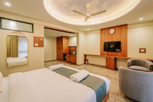 a bedroom with a bed and a tv and a couch at Hotel Urban Bella in Kozhikode