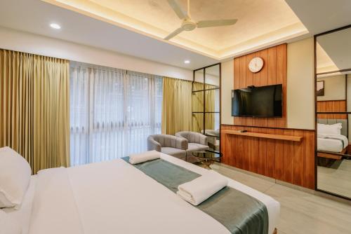a bedroom with a bed and a flat screen tv at Hotel Urban Bella in Kozhikode