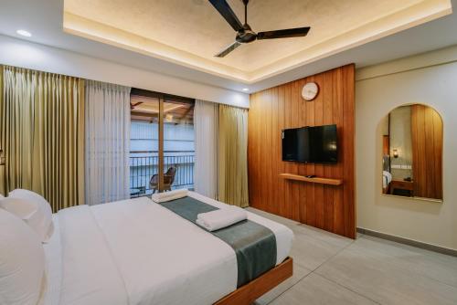 a bedroom with a bed and a flat screen tv at Hotel Urban Bella in Kozhikode