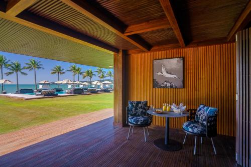 a porch with a table and two chairs and the ocean at Zendaya Resort Beach Sport & Spa in Búzios