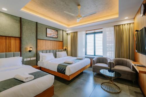 a hotel room with two beds and a chair at Hotel Urban Bella in Kozhikode