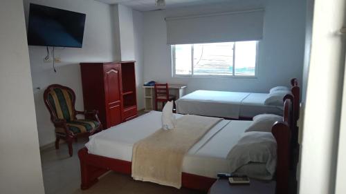 a bedroom with two beds and a tv and a chair at Hotel la mansión de acacias in Acacías