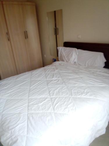 a large white bed with white sheets and pillows at Kigali aromas nice apartment in Kigali
