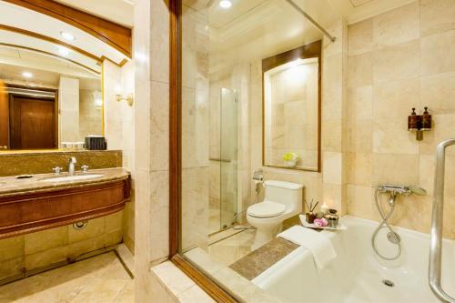 a bathroom with a tub and a toilet and a sink at Richmonde Hotel Ortigas, Manila in Manila