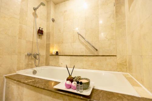 a bathroom with a tub and a shower and a sink at Richmonde Hotel Ortigas, Manila in Manila