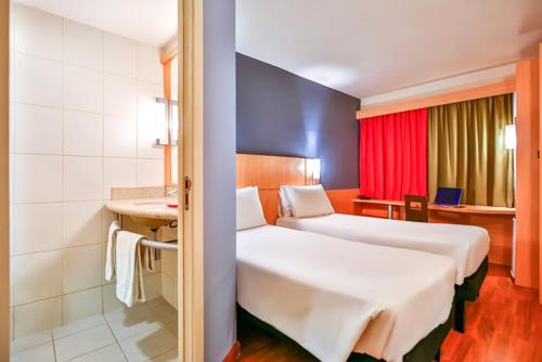 a hotel room with two beds and a bathroom at ibis Asuncion in Asuncion