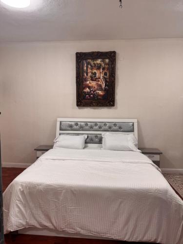 a bedroom with a white bed with a painting on the wall at رفيف باريس نجد in Unayzah