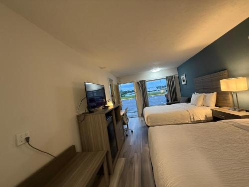 a hotel room with two beds and a television at Ramada by Wyndham Lumberton in Lumberton