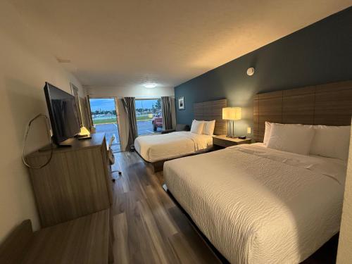 a hotel room with two beds and a flat screen tv at Ramada by Wyndham Lumberton in Lumberton