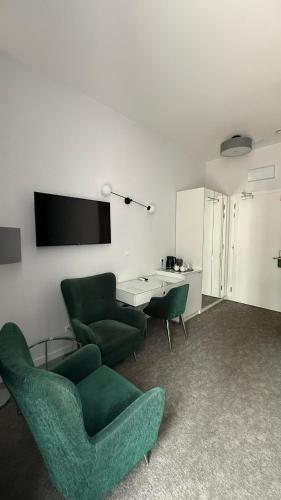 a living room with two green chairs and a tv at Stara Biblioteka in Wrocław