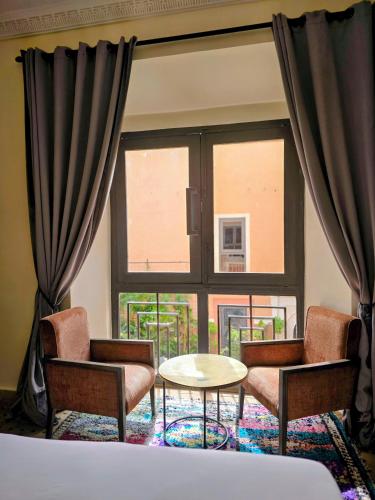 a room with two chairs and a table and a window at Riad Kasbah privilège and SPA in Marrakech