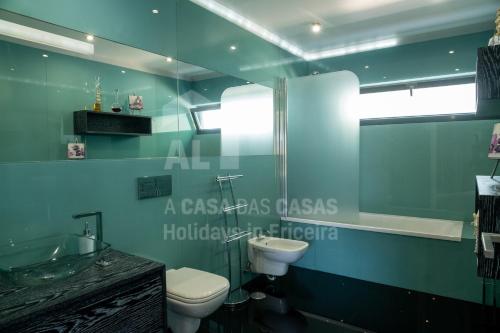 a green bathroom with a toilet and a sink at Aqua Villa by AcasaDasCasas in Ericeira
