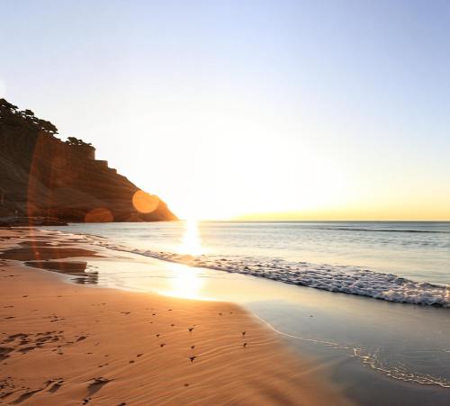 a beach with the sun rising over the ocean at Casa indipendente Roque Vista al mar con parking gratuito in Vallecrosia