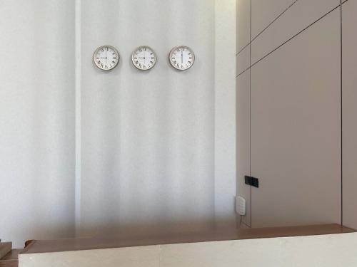 three clocks on the wall in a room at شقق خاصة بالقرب من برج الفيصلية in Riyadh