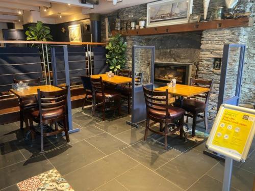 a restaurant with tables and chairs and a fireplace at Quinlan & Cooke Boutique Townhouse and QCs Seafood Restaurant in Cahersiveen
