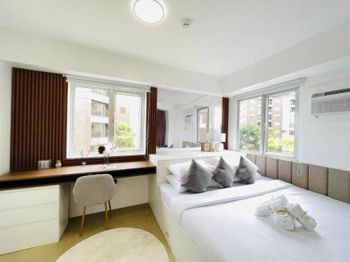 1 dormitorio con 1 cama blanca, escritorio y ventanas en Spacious Two Bedroom with Pool View - Iloilo, en Iloilo City