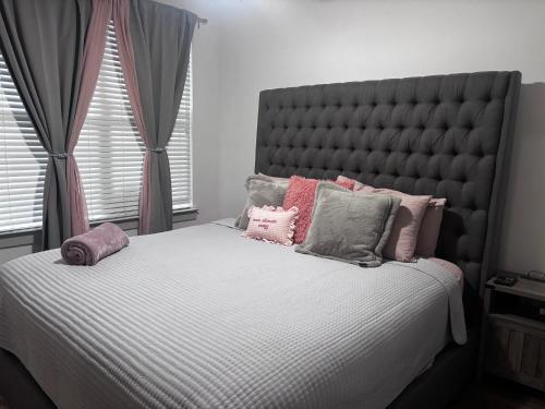 1 dormitorio con 1 cama grande con almohadas rosas y grises en Cozy Luxury Home, en Atlanta