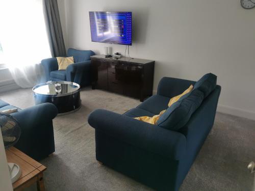 a living room with a blue couch and a tv at Newly amazing refurbished two bedroom apartment in Harrow on the Hill