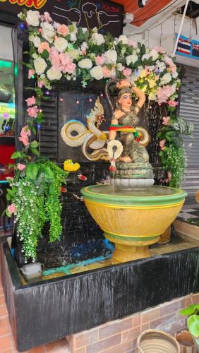 a fountain with a statue of a woman and flowers at Rich Bar & House in Pattaya