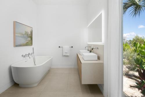 a bathroom with a tub and a sink and a bath tub at South Bank in Long Bay Hills
