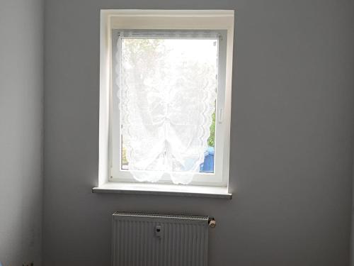 a window with a white curtain and a radiator at Large flat with separate rooms for 8 guests ST0 in Zeitz
