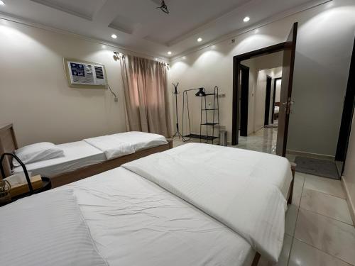 a bedroom with two beds and a mirror at Cozy 2-Bedroom Apartment in Batha Quraish in Makkah